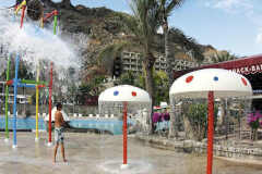 Young boy under the splash. Cafe snack bar on the right